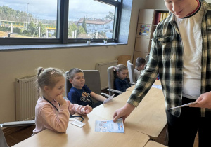 uczniowe rozdają dzieciom kolorowanki ze zwierzętami polarnym