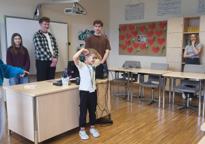 chłopiec pokazuje dzieciom wybrane zwierzę polarne w grze kalambury za nim stoją uczniowie