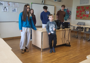 chłopiec pokazuje dzieciom wybrane zwierzę polarne w grze kalambury za nim stoją uczniowie