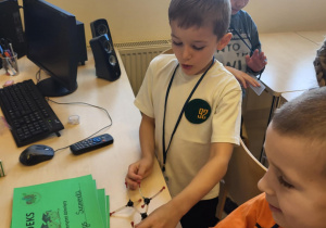 chłopcy stoją przy biurku, na którym leżą indeksy