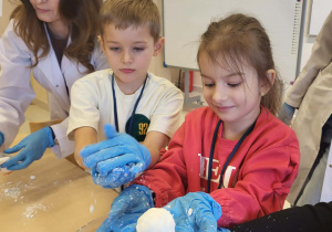 chłopiec i dziewczynka oraz pani od chemii lepią kulki śniegu