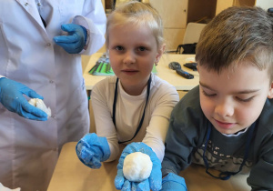 chłopiec i dziewczynka pokazują ulepione kulki śniegu