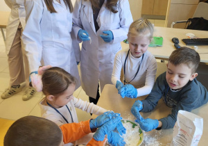 dzieci wraz z pania od chemii i uczenicami wykonują sztuczny śnieg