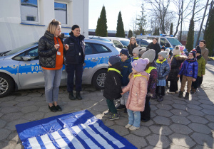 Pani tłumaczy dzieciom zasady bezpiecznego przechodzenia przez jezdnię