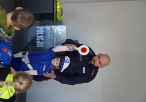 Wiktoria z panem policjantem podnosi lizak