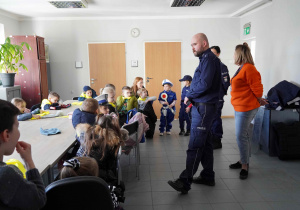 Pan policjant rozdaje sześciolatkom opaski odblaskowe
