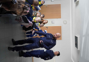 Pan policjant rozdaje sześciolatkom opaski odblaskowe