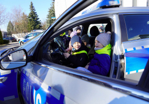Dzieci siedzą w radiowozie