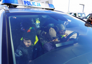 Dzieci siedzą w radiowozie