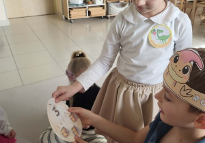 chłopiec z dziewczynką pokazują złączone połówki jaja dinozaura