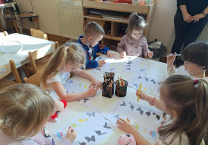 dzieci wykonują kartę pracy o dinozaurach