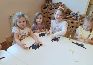dzieci wyklejają szkielet dinozaura