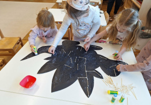 dzieci wyklejają szkielet dinozaura