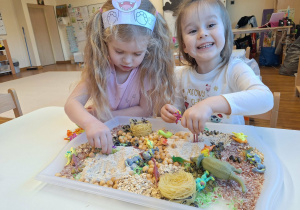 dzieci bawia sie dinozaurami na tacy sensorycznej