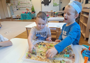 dzieci bawia sie dinozaurami na tacy sensorycznej