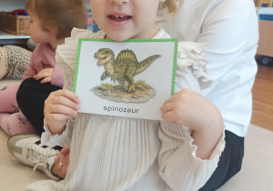 dziewczynka pokazuje dinozaura na obrazku