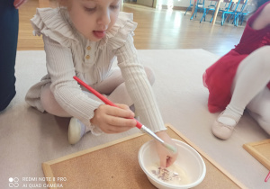 dziewczynka pędzelkiem usuwa kaszę