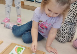 dziewczynka szuka odpowiedniego dinozaura