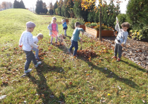Dzieci grabia liście grabiami 