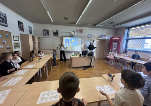 dzieci siedzą w ławkach patrząc i słuchając piosenki na temat pogody