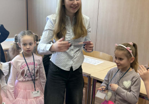 uczenica stoi wokół dzieci i tłumaczy zadanie do wykonania