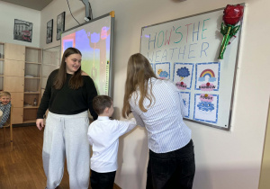 chłopczyk przyczepia do tablicy napis pogody do obrazka, pomiędzy nim stoją uczenice