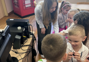 dzieci stoją przy uczenicy licuem i częstują się czekoladą