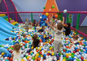 dzieci podrzucają kolorowe piłeczki