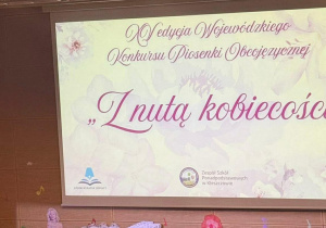 dzieci ubrane w żółte koszulki stoją na scenie a pięcioro z nich jest przebrane za kaczki, wykonując utrów "five little ducks'