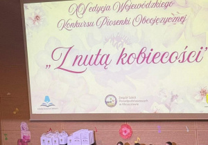 dzieci ubrane w żółte koszulki stoją na scenie a pięcioro z nich jest przebrane za kaczki, wykonując utrów "five little ducks'
