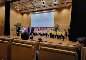 dzieci stoją na scenie i dostaja upominki wręczane przez Pania dyrekor ZSP w Kleszczowie