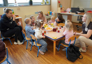 dzieci wraz z rodzicami siedzą przy stoliku podczas poczęstunku