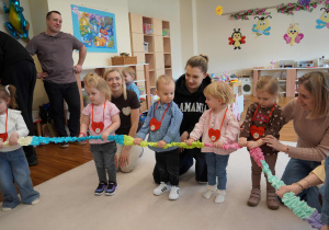 dzieci i rodzice trzymają slgumę