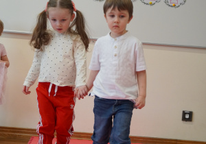 dziewczynka z chłopcem idą po czerwonym dywanie