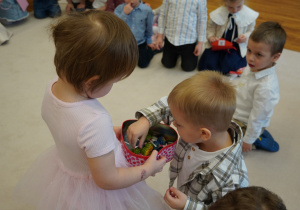 dziewczynka częstuje chłopca lizakami