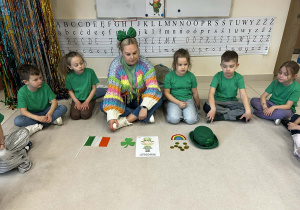 dzieci siedzą w kole razem z pania, ubrani na zielono i słuchają legendy o Św. Patryku aja opowies