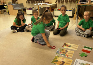 dzieci siedzą w kole, jedna dziewczyna jest na środku i układa z przedmiotów tęcze