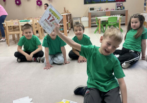 chłopiec siedzi w kole i pokazuje wylosowany obrazek z kartką kalendarza "17 March"