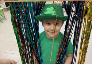 chłopiec stoi w tęczowej kurtynie z czapką skrzata