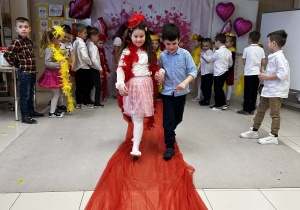 Chłopiec prowadzi koleżankę po czerwonym dywanie