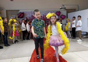 Chłopiec prowadzi koleżankę po czerwonym dywanie