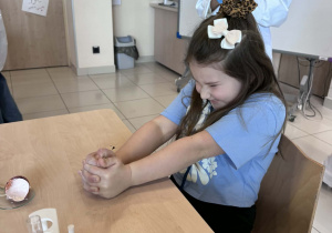 dziewczynka próbuje zgnieść jajko owinięte w folię aluminiową