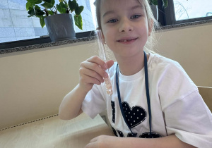 uśmiechnięta dziewczynka trzyma menzurkę