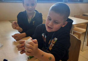 chłopiec próbuje zgnieść jajko