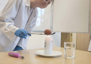 uczenica trzyma jajko nad święcą, pokazując jak zmienia kolor