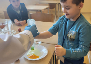 chłopiec wykonuję doświadczenie z butelka i jajkiem