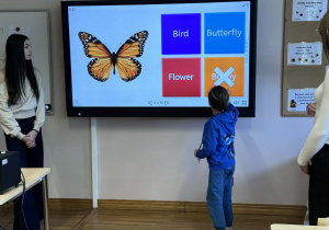 chłopiec zaznacza na tablicy multimedialnej podpis do obrazka