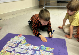 Chłopiec podpisuje się na grupowym plakacie