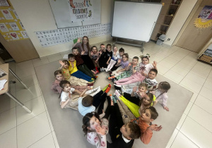 Dzieci siedzą na dywanie i prezentują kolorowe skarpetki nie do pary