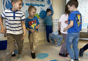 Dzieci chodzą wokół niebieskich kartek